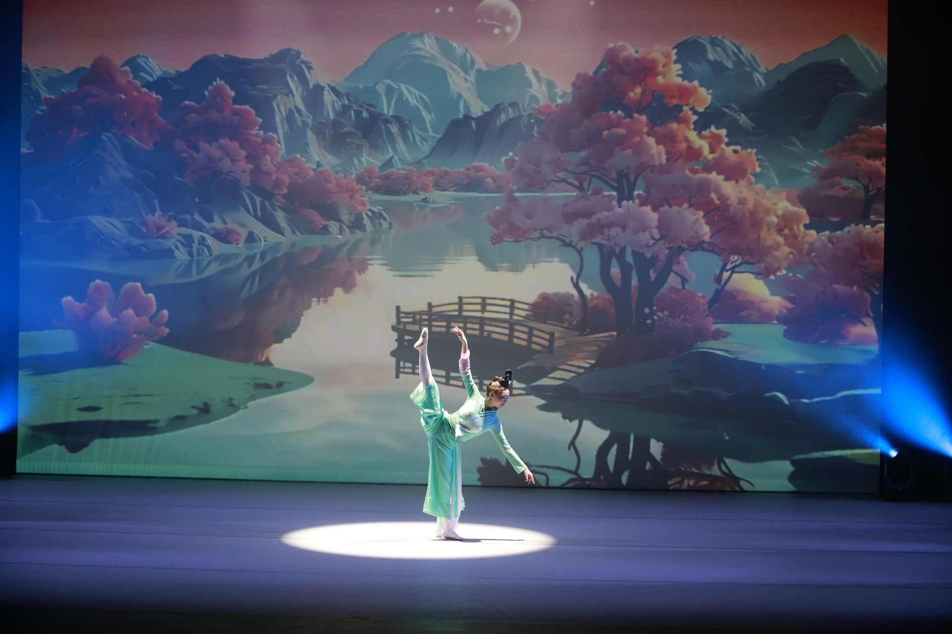 Classical dancer in green silk, arabesque under spotlight