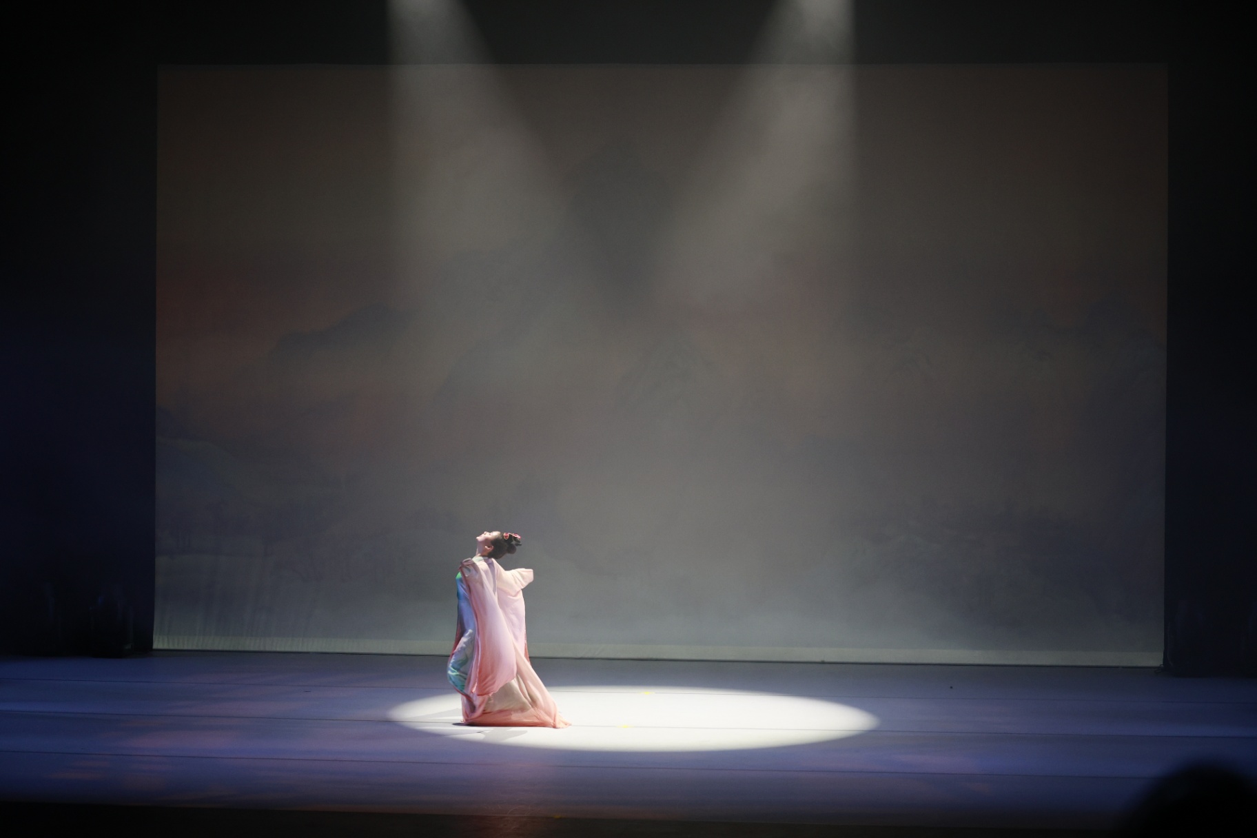 Soloist in pale silk beneath a single spotlight